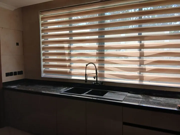 Alternating translucent and opaque blind bands control light at a kitchen window.