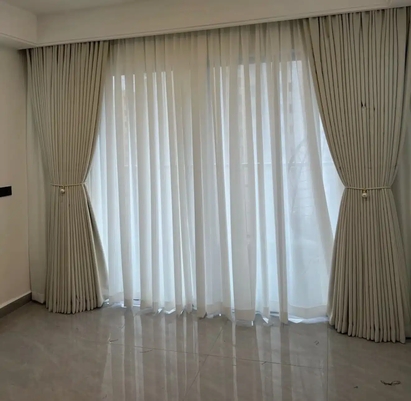 Cream curtains and white sheers across a wide opening