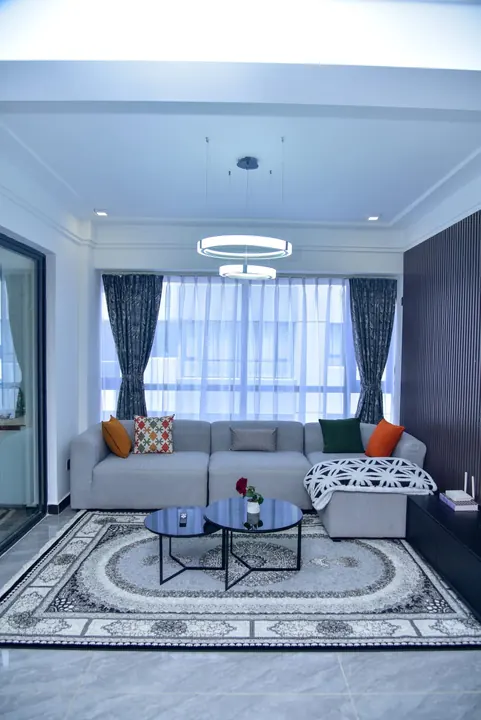 Patterned curtains and sheers coordinate with the furniture and rug in a living room.