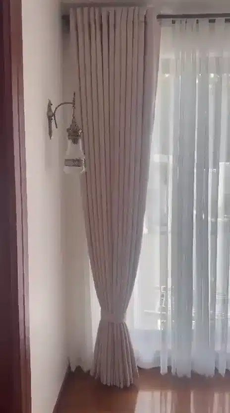 See the folds, tieback and sheer layer of a full-length window treatment.