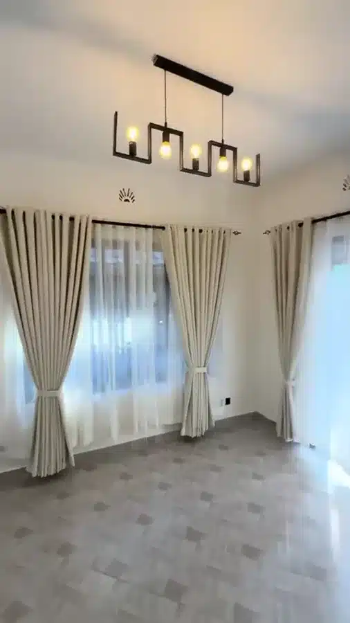 A brief room view showing light curtains and sheers across adjoining windows.