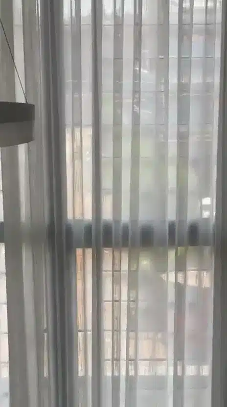 A close moving view of daylight filtering through a sheer curtain.